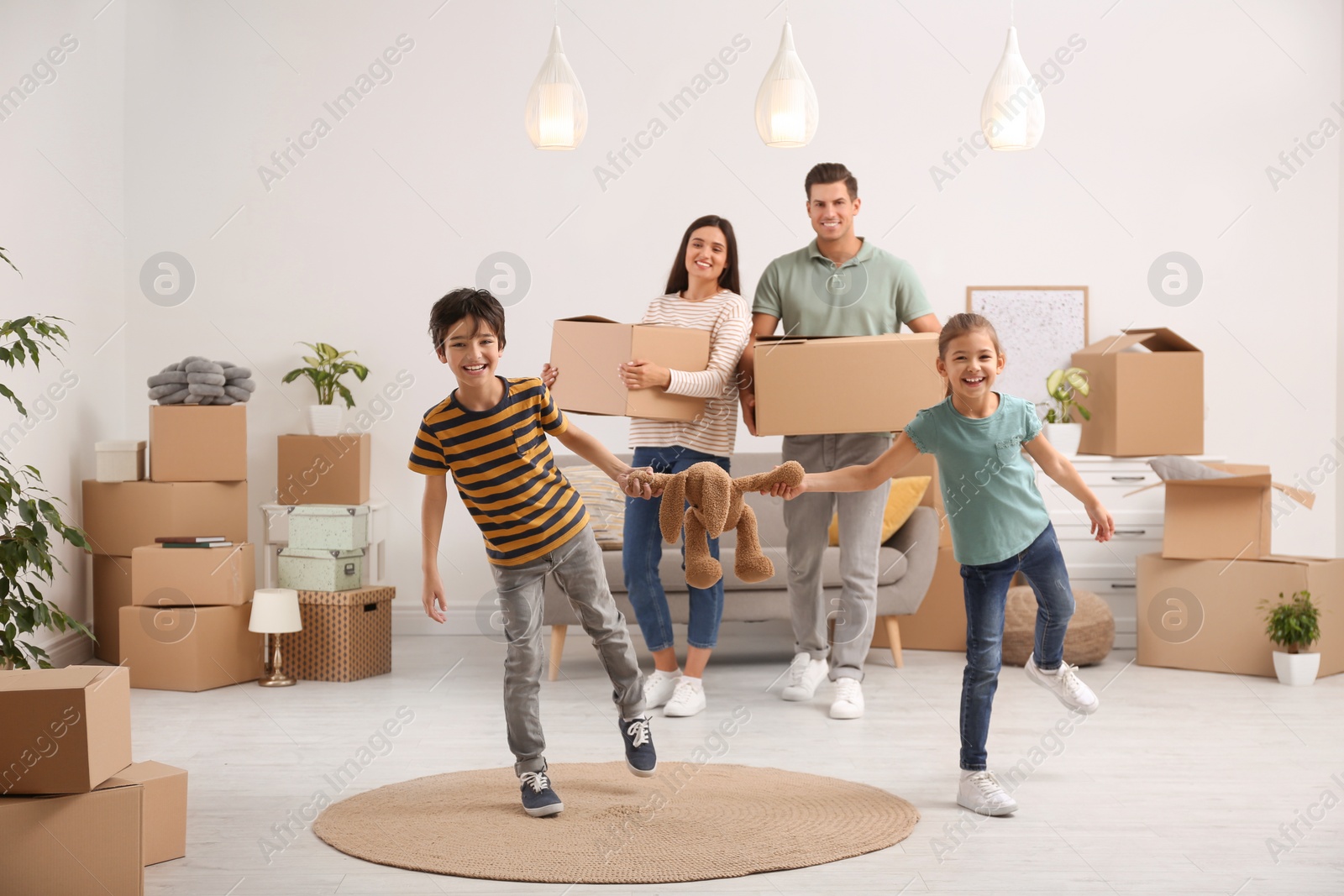 Photo of Happy family in room with cardboard boxes on moving day