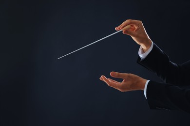 Photo of Professional conductor with baton on black background, closeup. Space for text