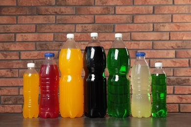 Photo of Bottles of soft drinks on table near brick wall