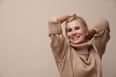 Happy woman in stylish sweater on beige background. Space for text