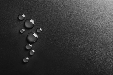 Photo of Water drops on black background, top view. Space for text