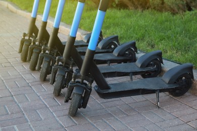 Photo of Many modern electric scooters parked on pavement. Rental service