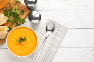 Photo of Flat lay composition with pumpkin cream soup in bowl on wooden background. Space for text