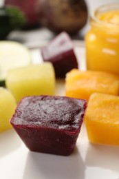 Frozen beet, pumpkin and zucchini puree cubes on table, closeup