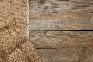 Burlap fabric on wooden table, top view. Space for text