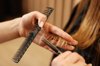 Photo of Professional hairdresser cutting girl's hair in beauty salon, closeup