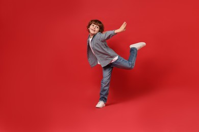 Happy little boy dancing on red background