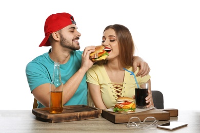 Photo of Happy couple having lunch with burgers at table on white background