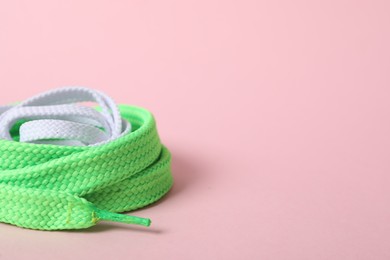 Mint and white shoe laces on light pink background, closeup. Space for text