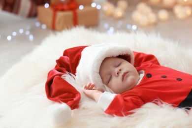 Photo of Cute baby in Christmas costume sleeping on fur rug