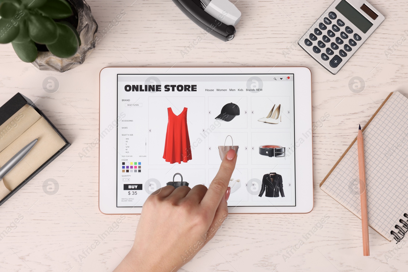 Photo of Woman with tablet shopping online at white wooden table, top view