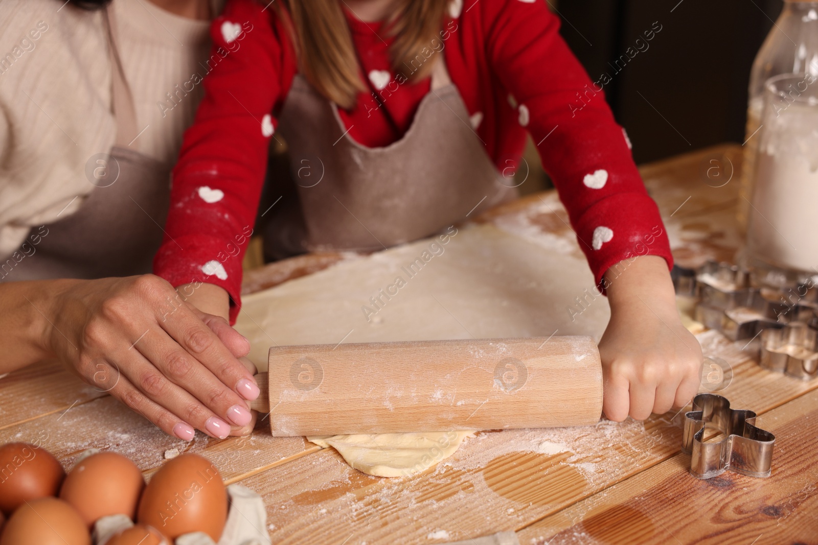 Photo of Mother and her daughter making delicious Christmas cookies at wooden table, closeup