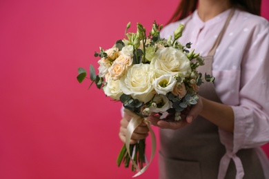 Photo of Florist holding beautiful wedding bouquet on pink background, closeup. Space for text