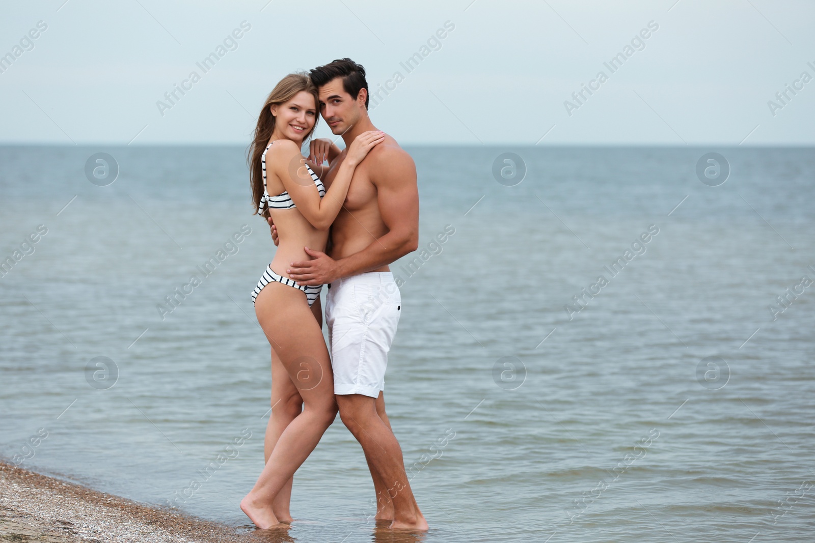 Photo of Happy young couple spending time together on sea beach. Space for text