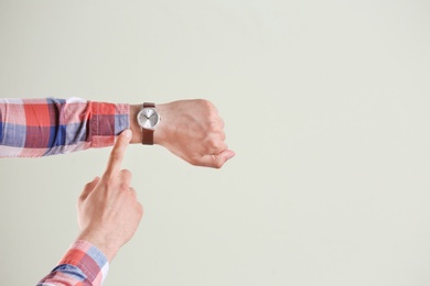 Young man with wristwatch on grey background. Time concept