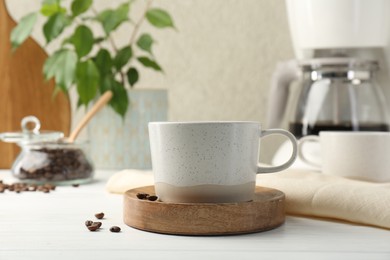 Photo of Cup of drink and coffee beans on white wooden table