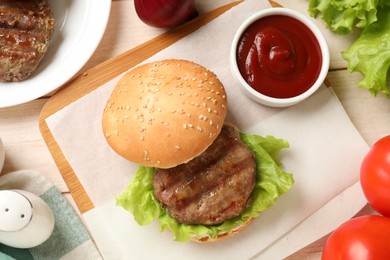 Photo of Delicious fried patty, lettuce, buns and sauce on wooden table, flat lay. Making hamburger