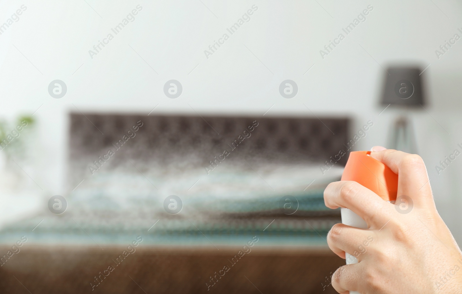 Photo of Woman spraying air freshener in bedroom