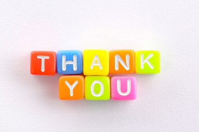 Photo of Phrase Thank You made of colorful cubes on white table, top view
