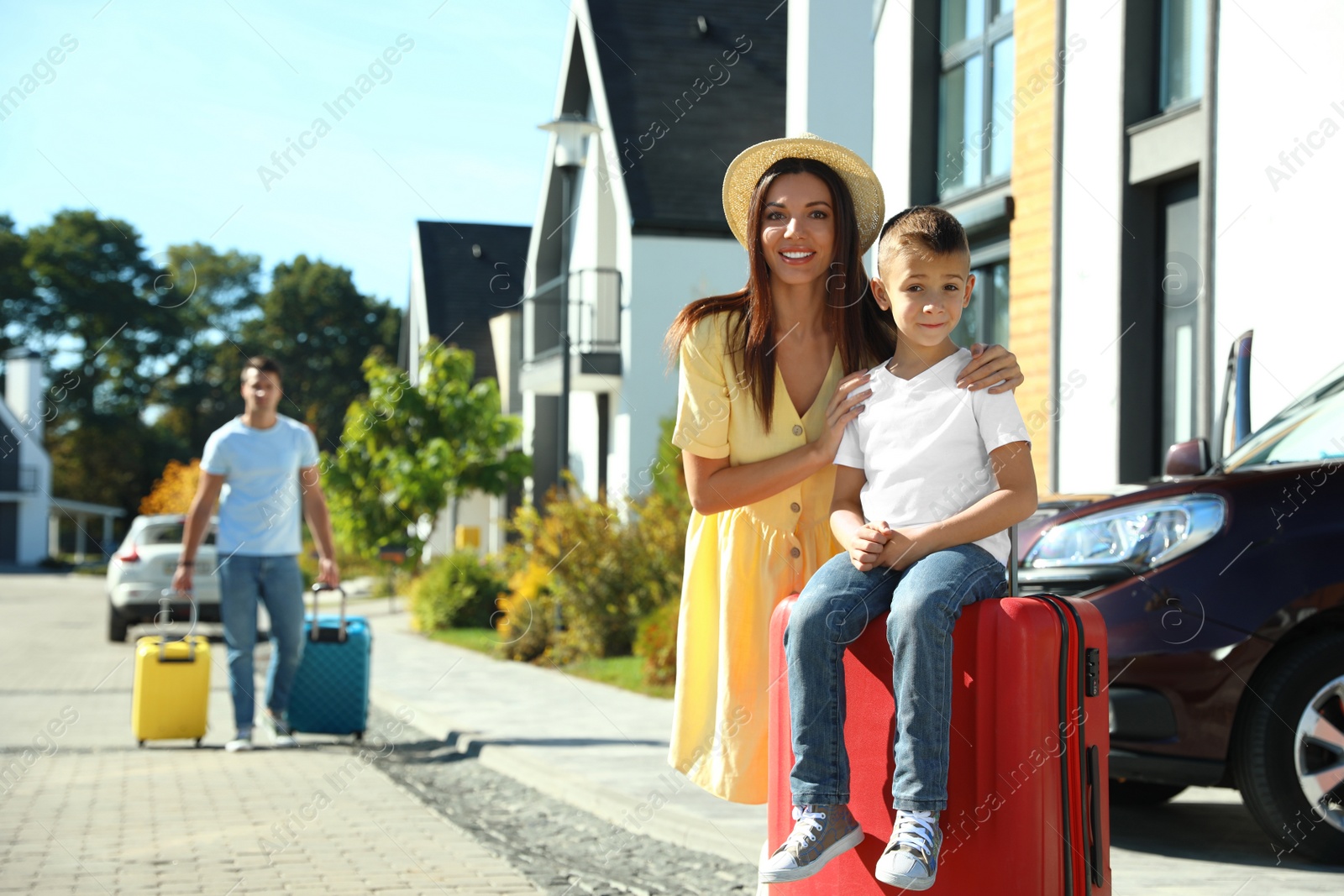 Photo of Happy family with suitcases near house outdoors. Moving day