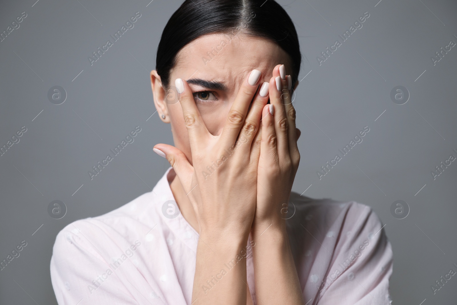 Photo of Young woman feeling fear on grey background, closeup