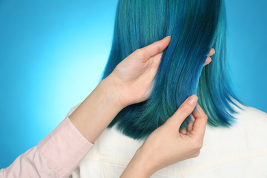 Woman with bright dyed hair on light blue background, back view