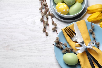 Photo of Festive Easter table setting with eggs on white wooden background, flat lay. Space for text