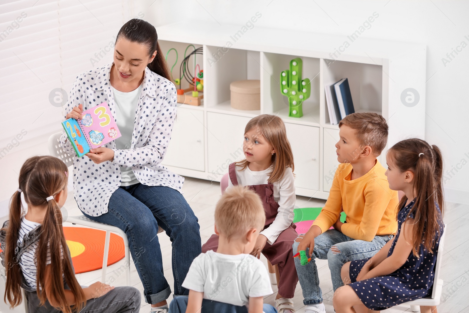 Photo of Nursery teacher and group of cute little children learning numbers in kindergarten. Playtime activities