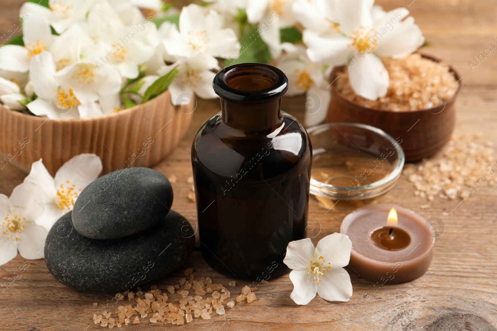 Photo of Beautiful composition with jasmine essential oil and fresh flowers on wooden table