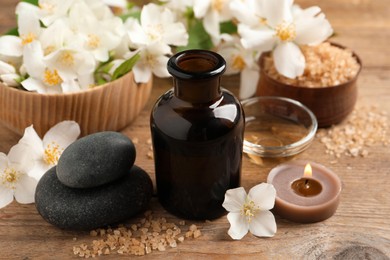 Beautiful composition with jasmine essential oil and fresh flowers on wooden table