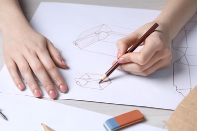 Woman creating packaging design at light wooden table, closeup