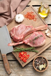 Photo of Fresh tomahawk beef cuts, butcher knife and spices on wooden table, top view