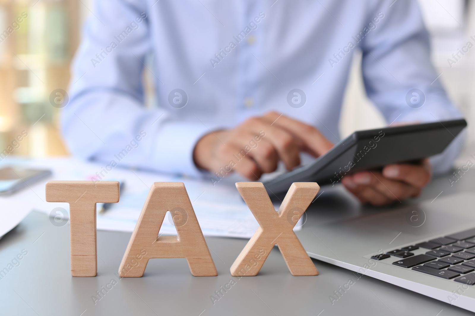 Photo of Word TAX and blurred accountant on background