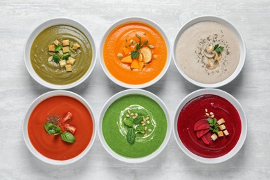 Various soups in bowls on wooden background, top view. Healthy food