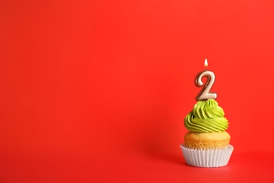 Photo of Birthday cupcake with number two candle on red background, space for text