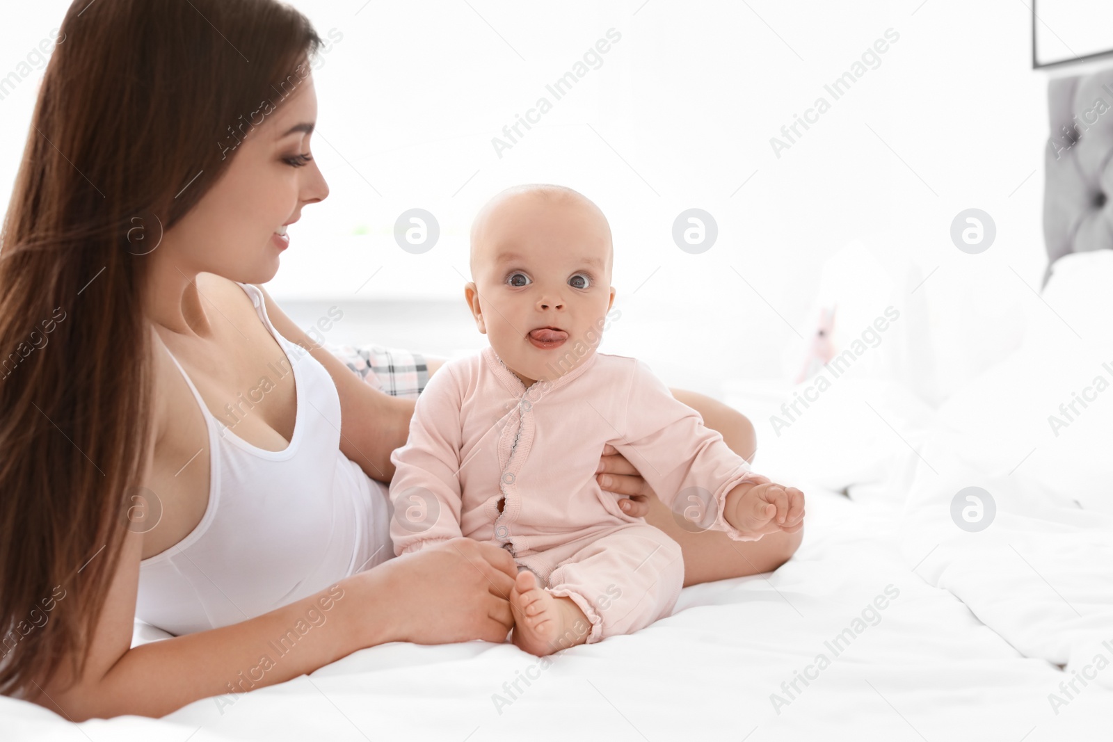 Photo of Young mother with her cute baby girl on bed at home