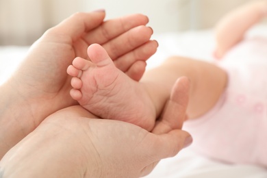 Photo of Mother holding baby's foot on bed, closeup