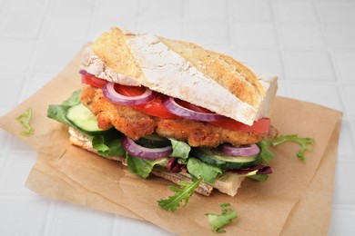 Delicious sandwich with schnitzel on white tiled table, closeup