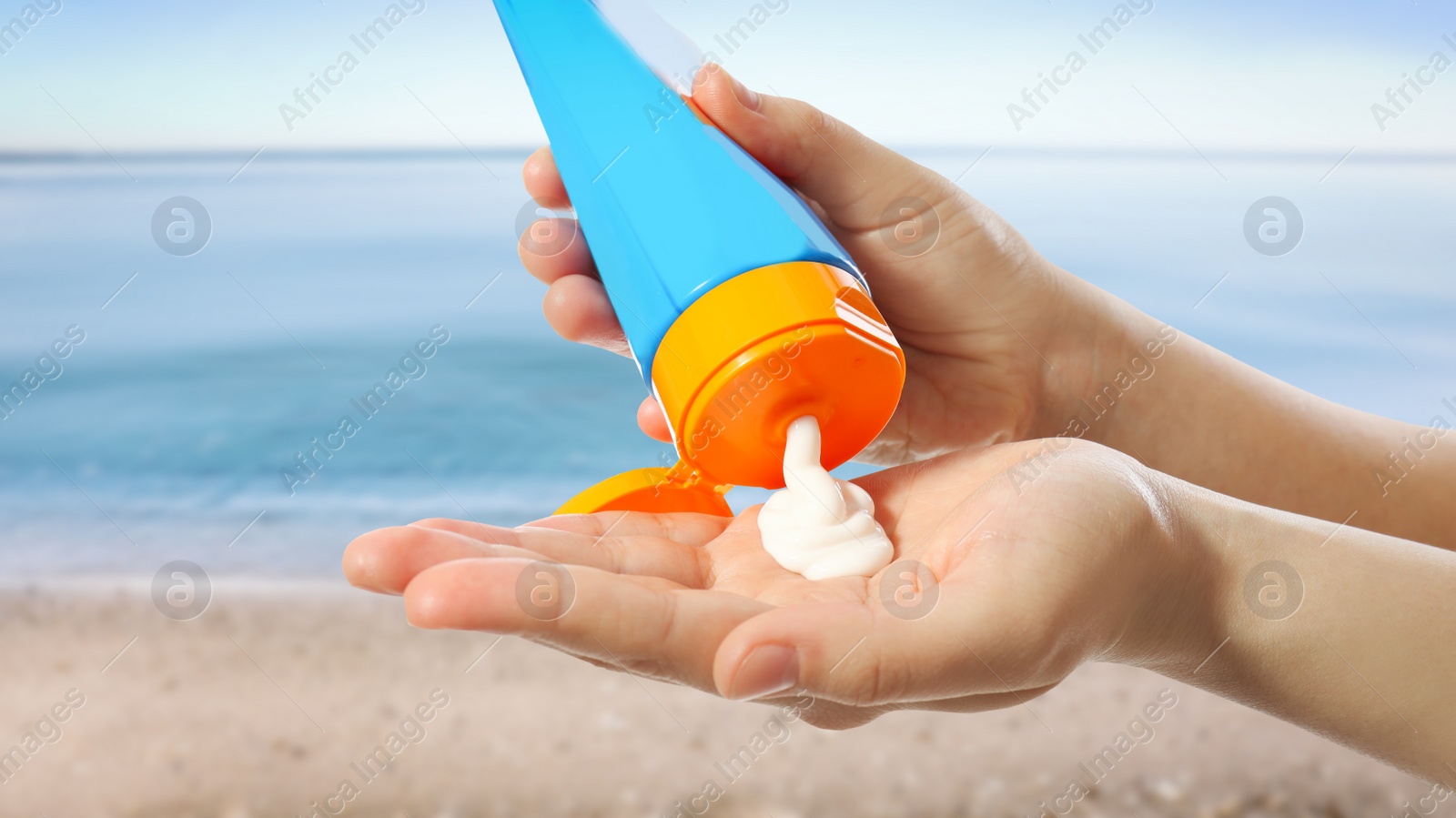 Image of Young woman applying sun protection cream near sea, closeup