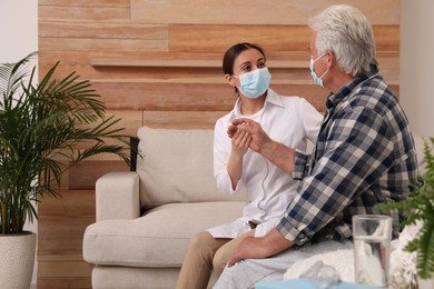 Doctor taking care of senior man with protective mask at nursing home