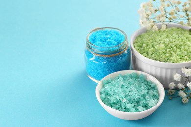 Aromatic sea salt and beautiful flowers on light blue background. Space for text