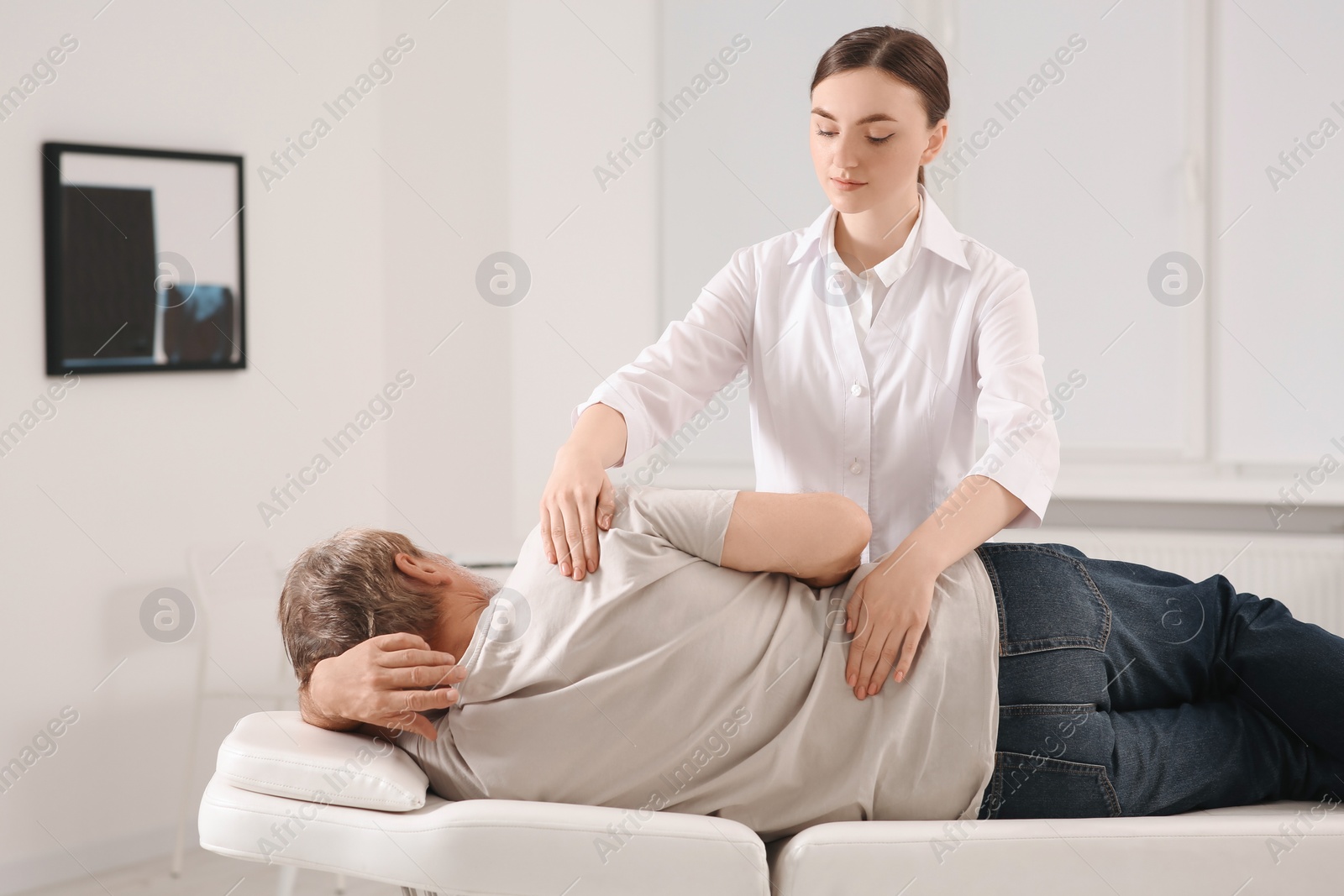 Photo of Professional orthopedist examining patient's back in clinic