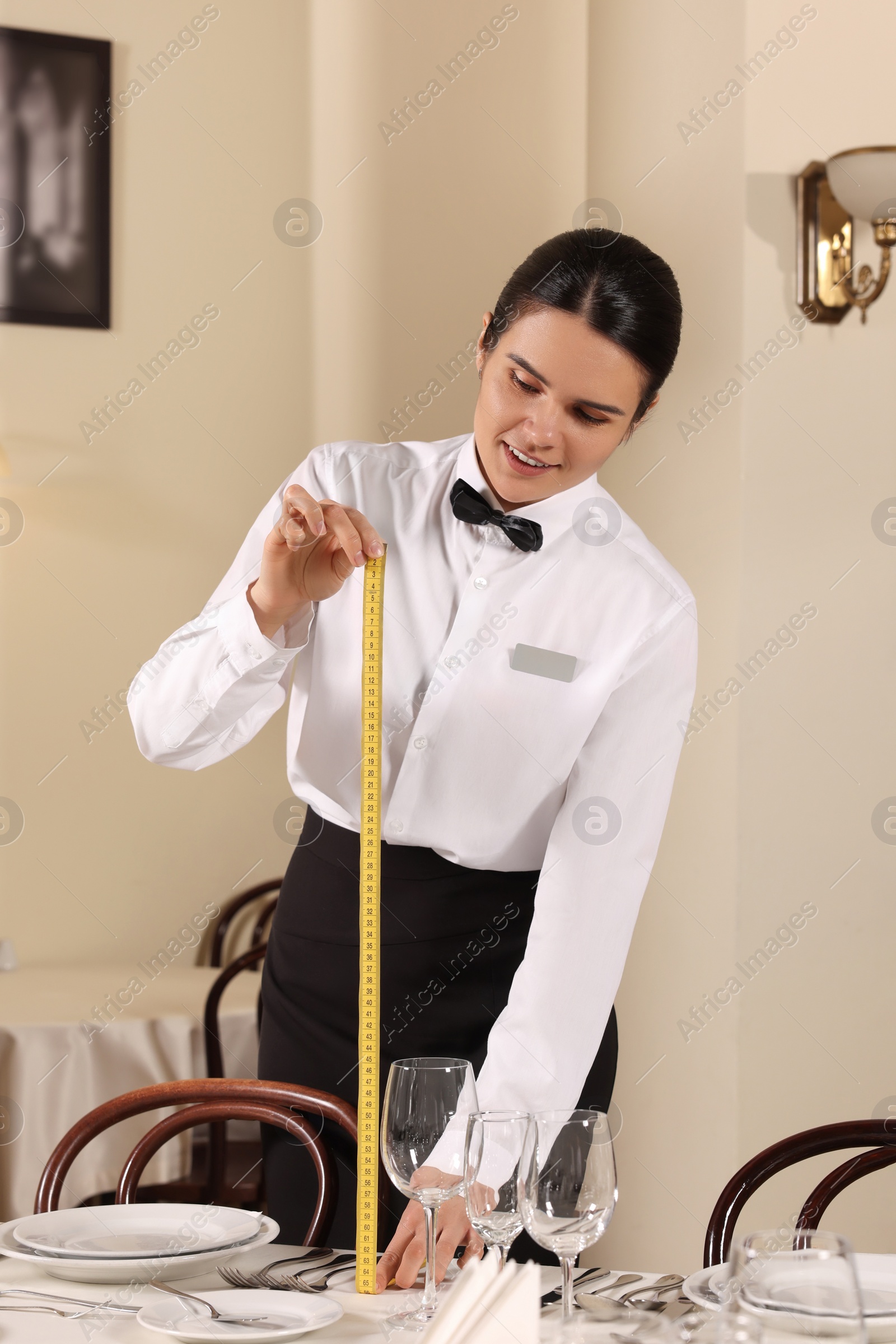 Photo of Woman setting table in restaurant. Professional butler courses