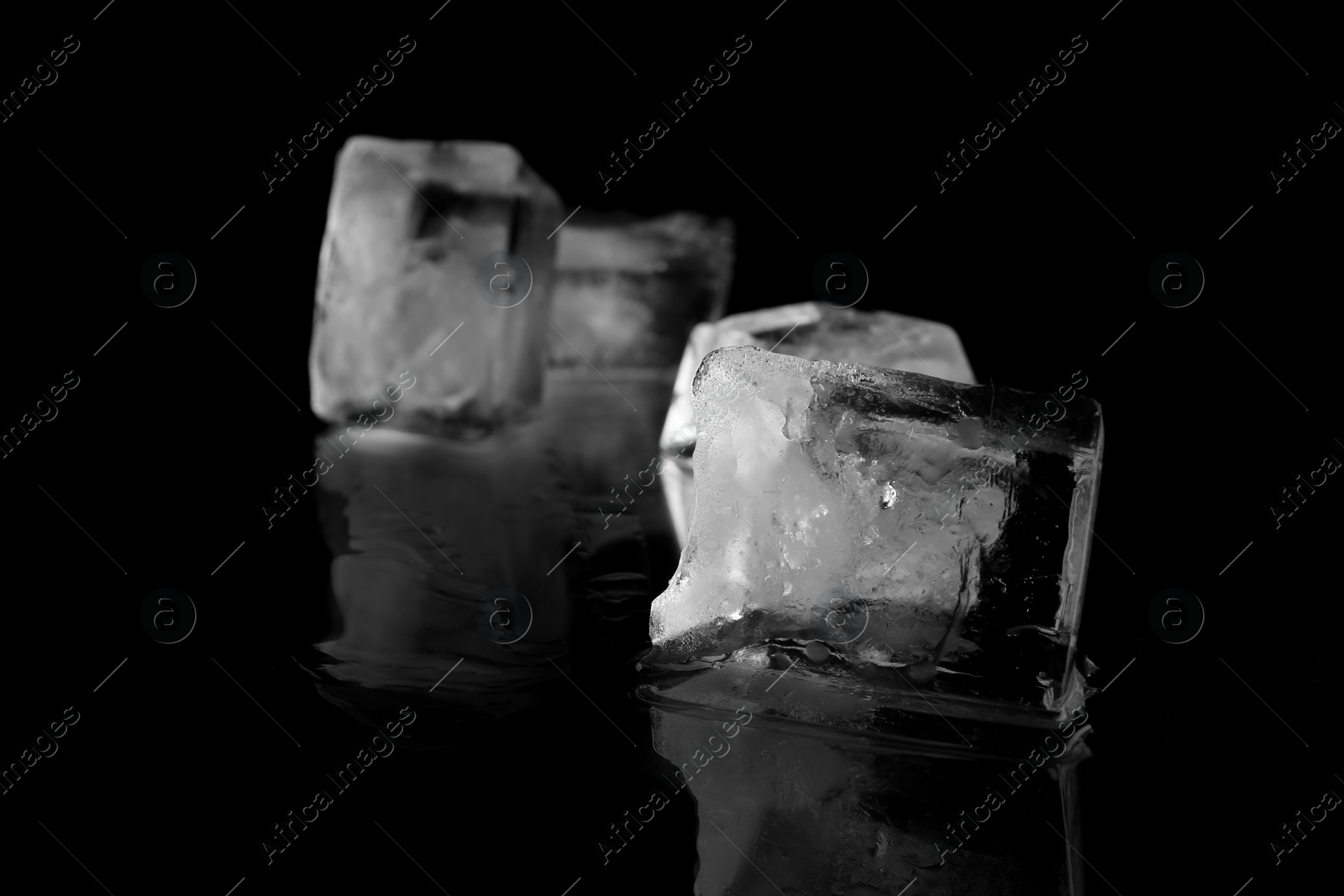 Photo of Transparent ice cube on black mirror surface