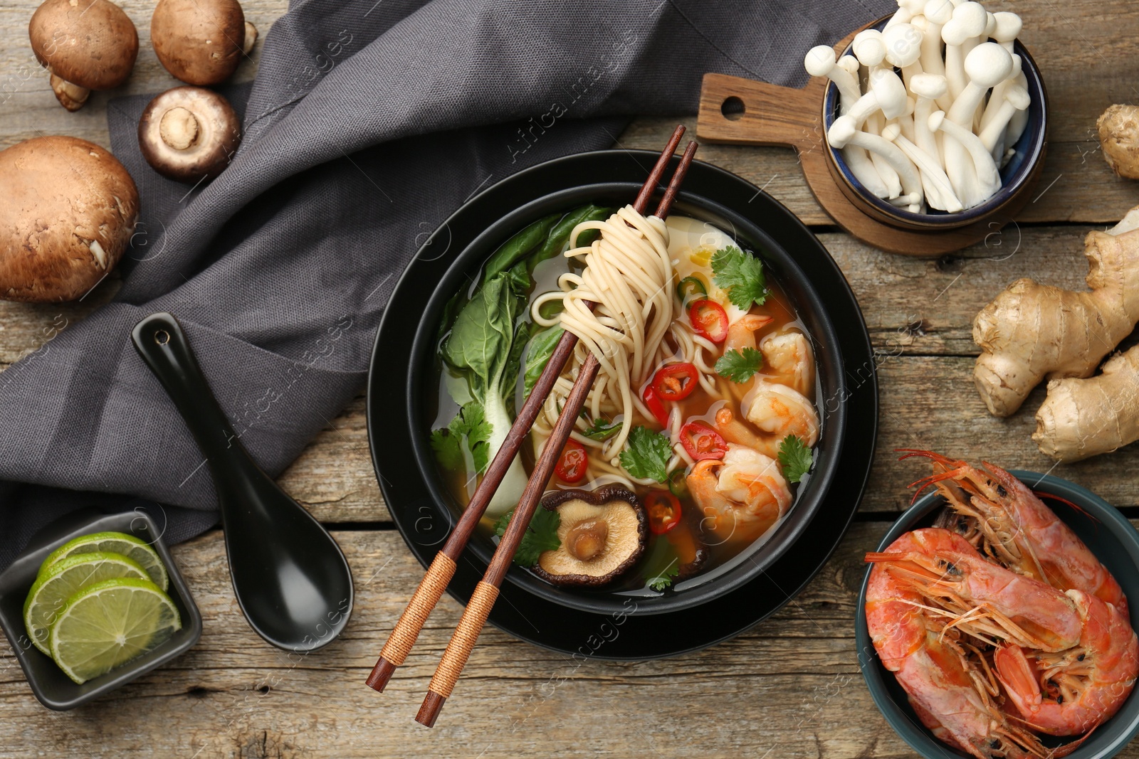 Photo of Flat lay composition with delicious ramen in bowl and ingredients on wooden table. Noodle soup