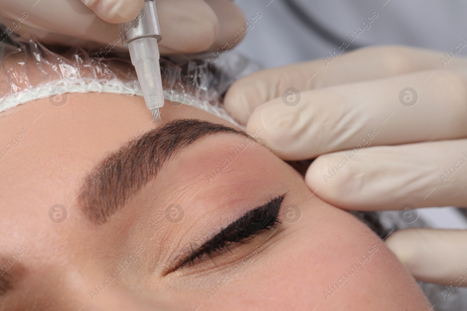 Photo of Young woman during procedure of permanent eyebrow makeup, closeup