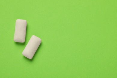 Photo of Chewing gum pieces on green background, flat lay. Space for text