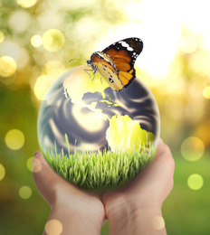 Image of Woman holding Earth with butterfly outdoors, closeup