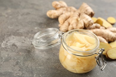 Spicy pickled ginger and root on light grey table, closeup. Space for text