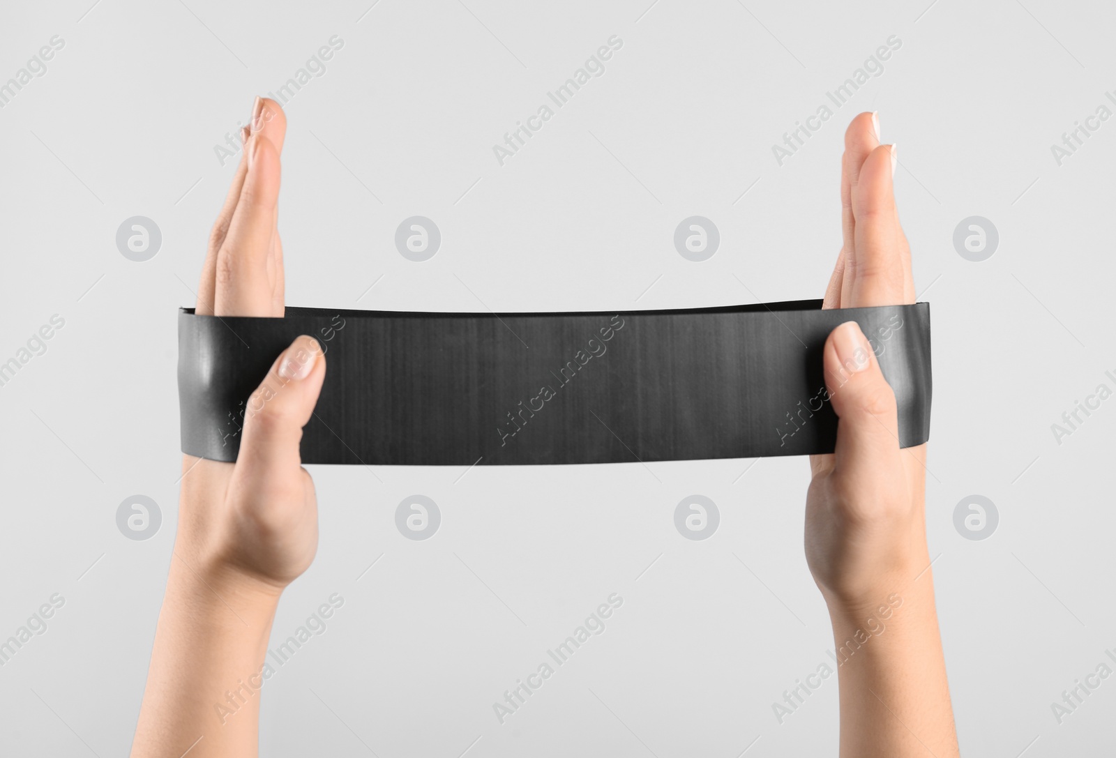 Photo of Woman with fitness elastic band on light grey background, closeup